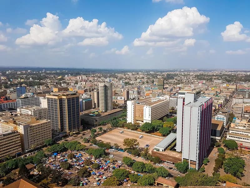Aerial view of a dense city center with high-rise towers, open plaza, and market stalls