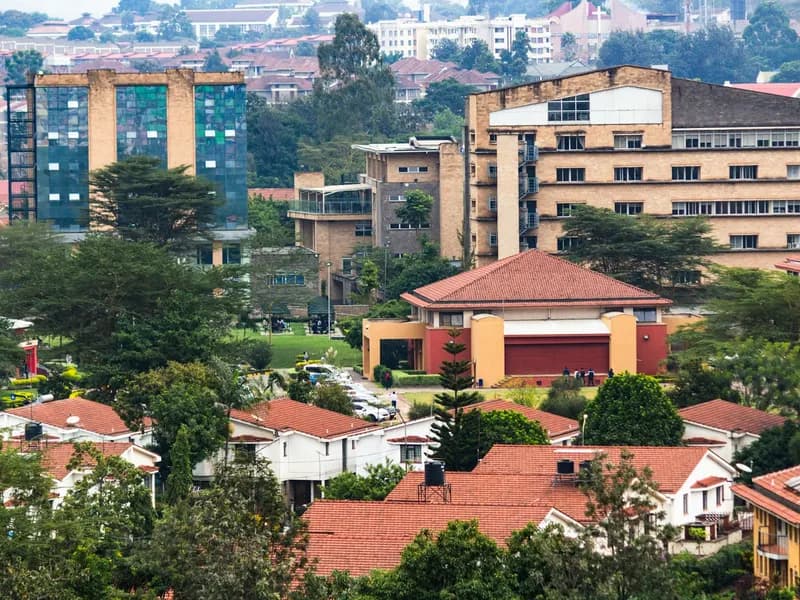 Red-tiled rooftops and modern buildings amid green trees in a hillside city