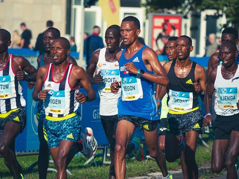 Group of runners in race singlets competing on a street during a marathon