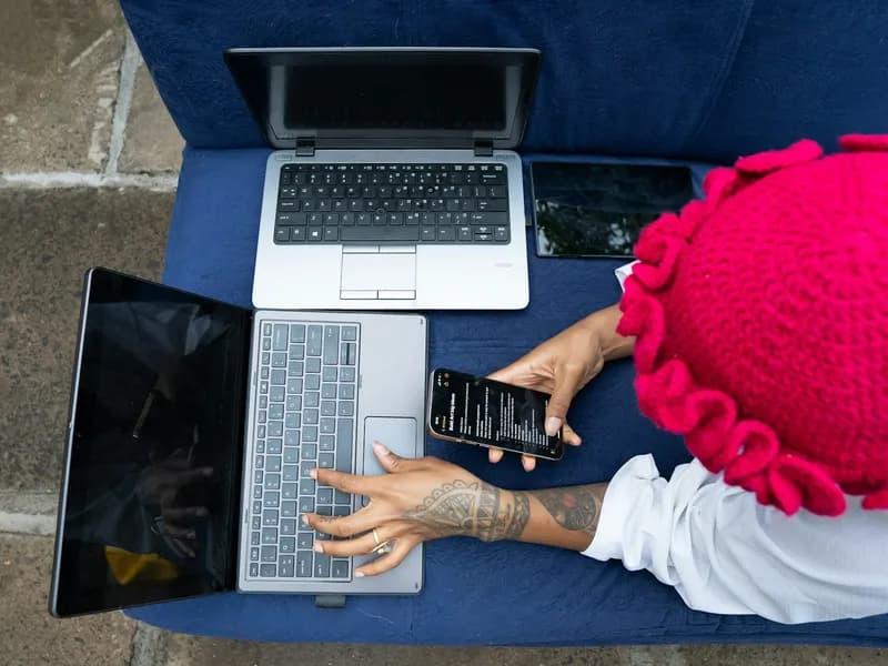 Person works on multiple laptops and a phone
