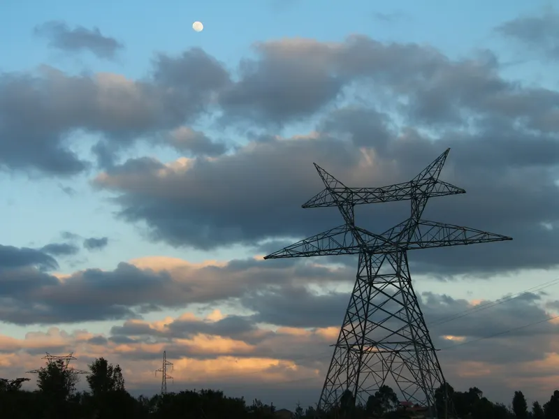 a high voltage power line with a full moon in the background