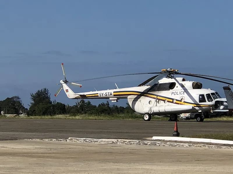 White police helicopter with yellow and black stripes parked on an airfield apron